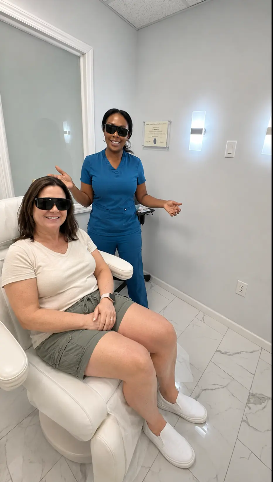 Patient wearing protective eyewear seated beside a smiling laser technician before a laser session in Englewood, NJ