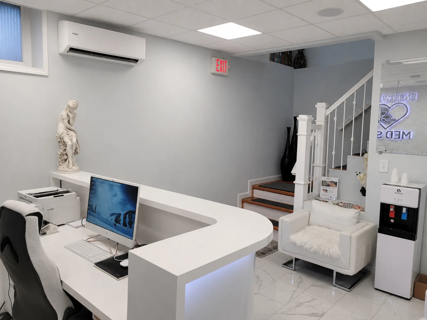 Front desk and patient lounge with white leather seating and water station inside the Englewood, NJ medical spa